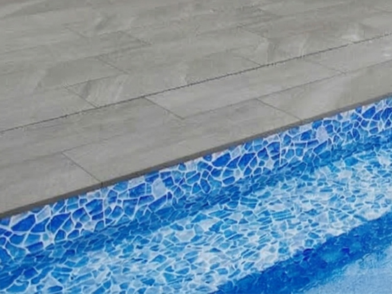 Närbild på granitkeramik kvartsit mörkgrå poolkantsten till pool