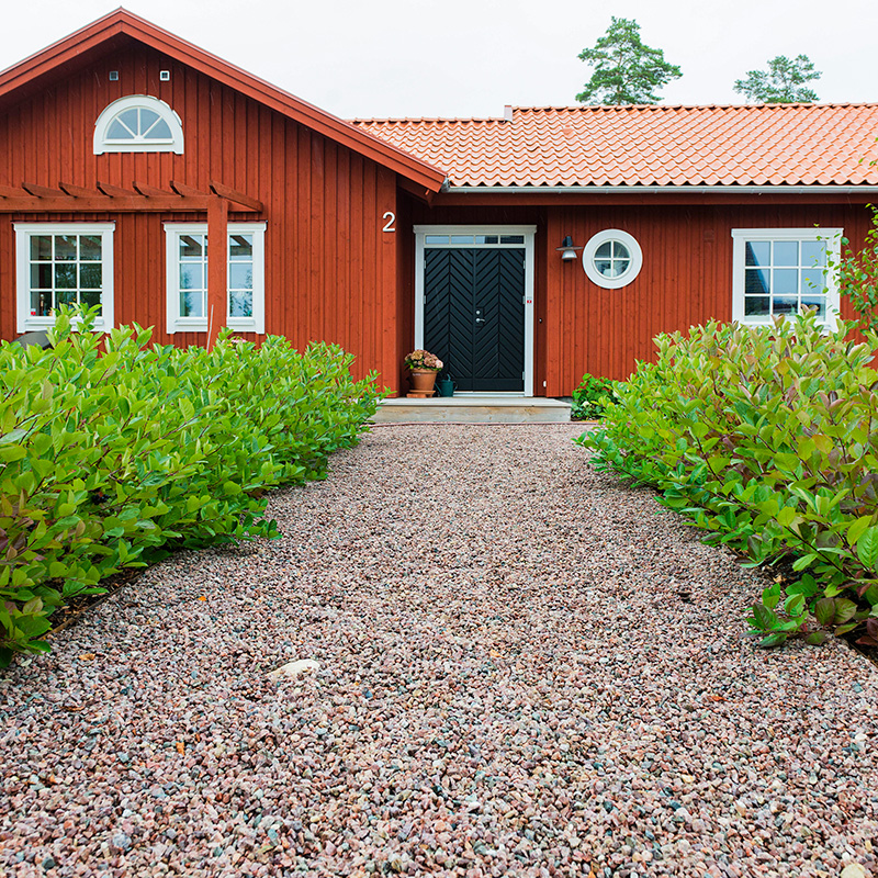 Trädgårdsgång med naturröd gårdsgrus mot husentré 