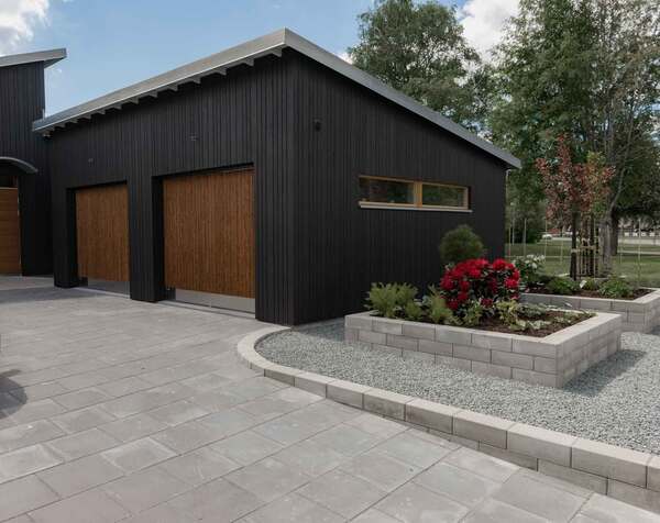 Grå mursten Basicmur och stenrabatt med Diabskross vid uppfart med marksten Funkis upp mot ett hus.