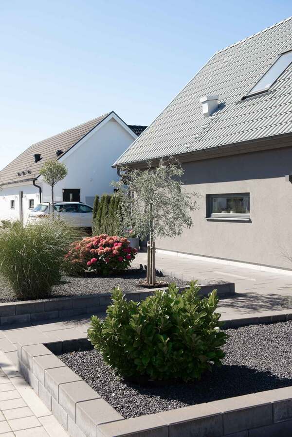 Grå mur med mursten Basicmur runt stenrabatt med Diabaskross.