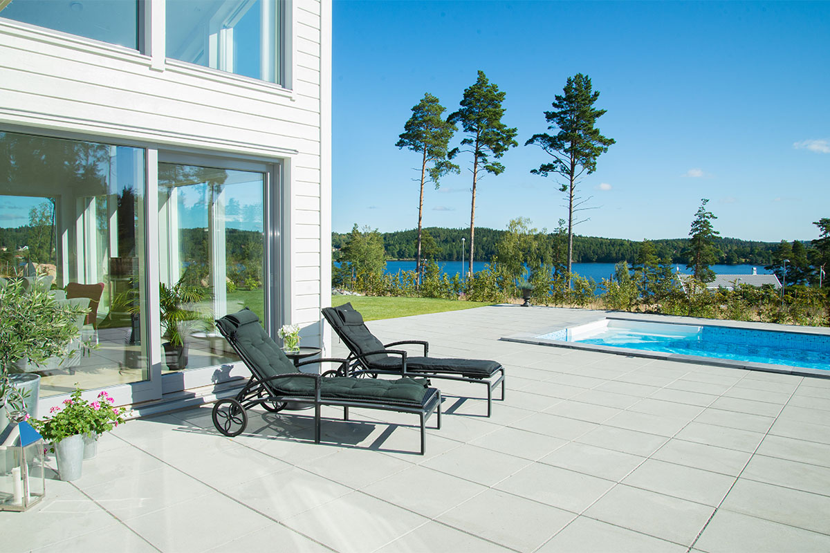 Poolområde med grå marksten Funkis 60x60 cm, utsikt över en sjö