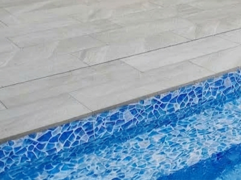 Närbild på granitkeramik kvartsit ljusgrå poolkantsten till pool