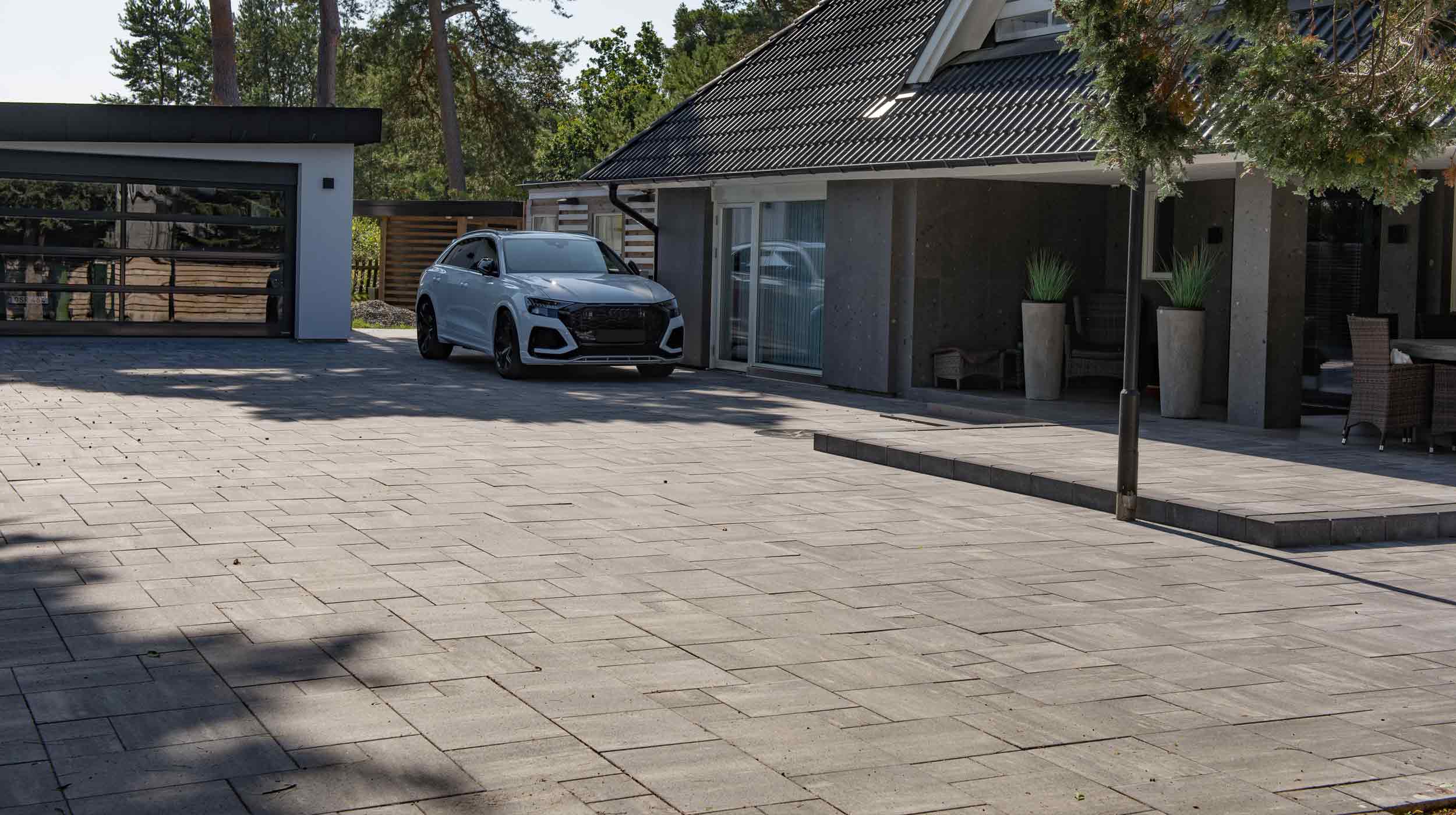 Marksten på en stor uppfart mot garage och hus.